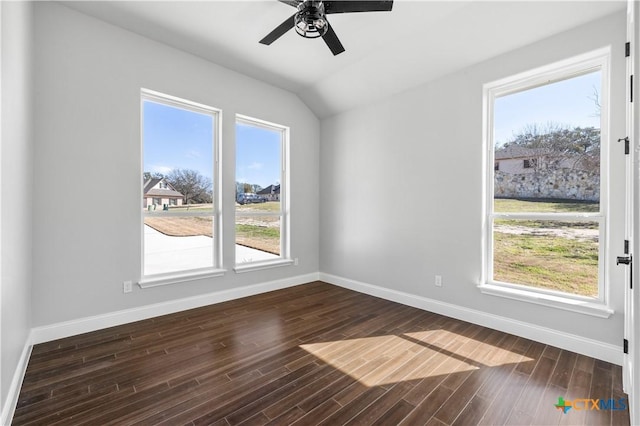 spare room featuring lofted ceiling, dark wood-style flooring, plenty of natural light, and baseboards