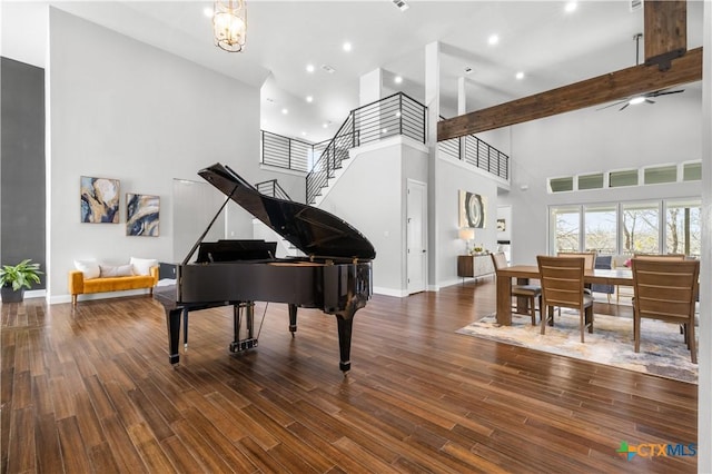 interior space featuring a notable chandelier, a high ceiling, wood finished floors, baseboards, and stairway