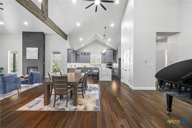 dining room featuring dark wood-style floors, plenty of natural light, high vaulted ceiling, and a tiled fireplace