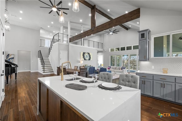 6817 Misty Creek Ln, Temple, TX 76502 - kitchen with gray cabinetry, a ceiling fan, open floor plan, a kitchen island with sink, and high vaulted ceiling
