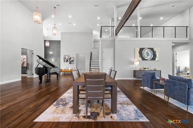 dining area with wood finished floors, a high ceiling, and stairs