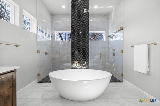 bathroom featuring marble finish floor, vanity, a freestanding bath, and a stall shower