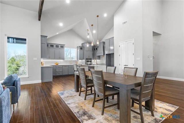 dining room with dark wood-style floors, high vaulted ceiling, and baseboards