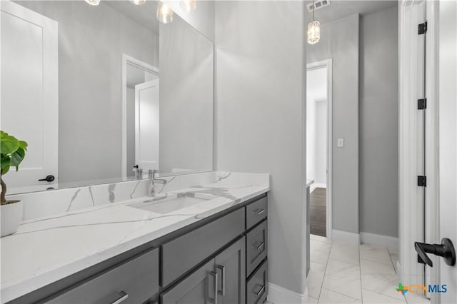 bathroom with marble finish floor, vanity, and baseboards