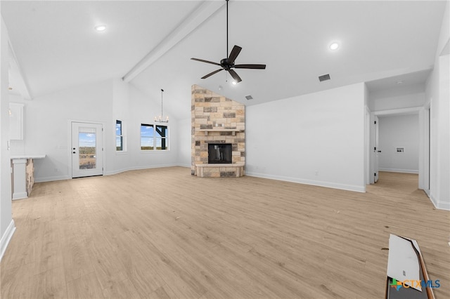 unfurnished living room with a stone fireplace, high vaulted ceiling, beamed ceiling, ceiling fan, and light hardwood / wood-style flooring