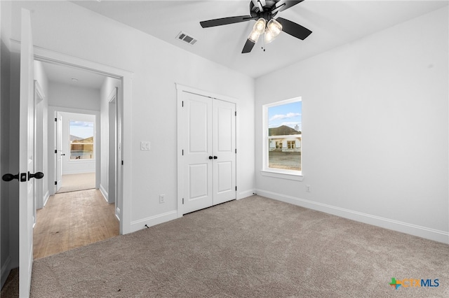 unfurnished bedroom with ceiling fan, a closet, and light colored carpet