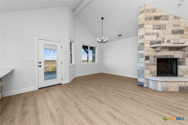 unfurnished living room featuring beam ceiling, high vaulted ceiling, a fireplace, a chandelier, and light wood-type flooring