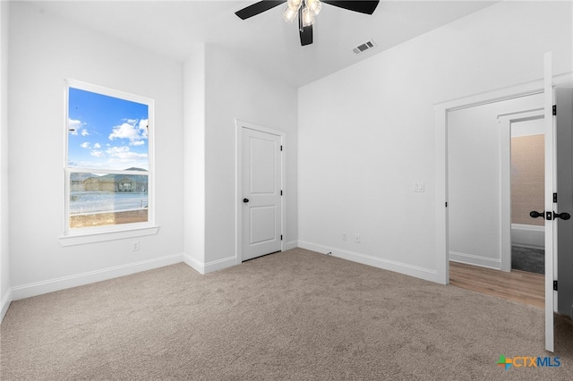 carpeted spare room featuring ceiling fan and a water view