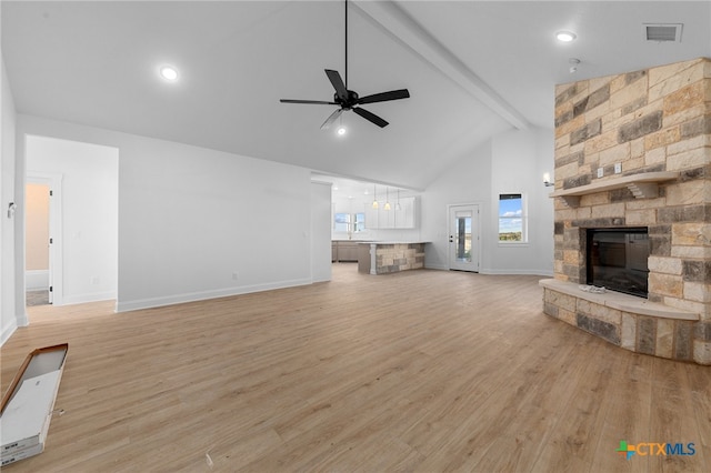 unfurnished living room with a fireplace, beam ceiling, high vaulted ceiling, ceiling fan, and light hardwood / wood-style flooring