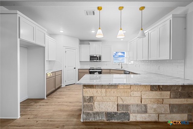 kitchen with white cabinets, kitchen peninsula, appliances with stainless steel finishes, and sink