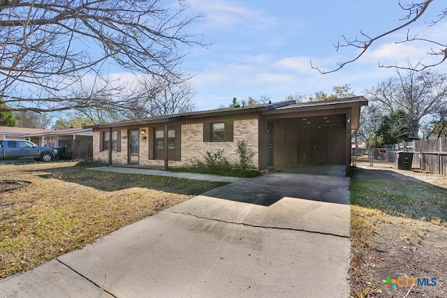 view of front facade featuring a front yard, an attached carport, concrete driveway, and brick siding