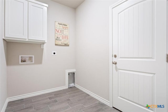 washroom featuring hookup for an electric dryer, washer hookup, light hardwood / wood-style floors, and cabinets