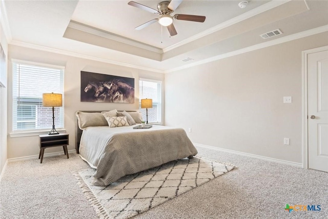 carpeted bedroom with ceiling fan, a raised ceiling, ornamental molding, and multiple windows