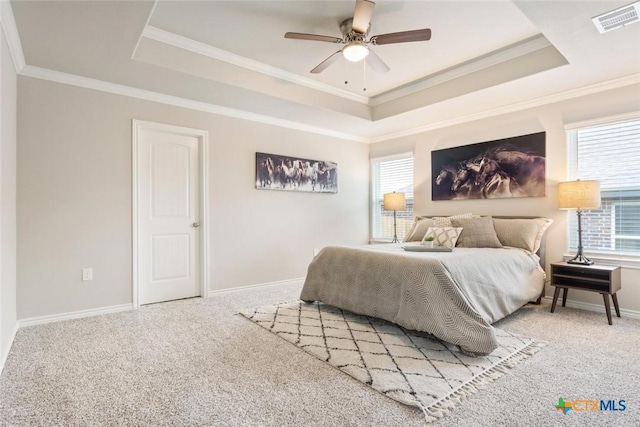 bedroom with ceiling fan, multiple windows, and a tray ceiling