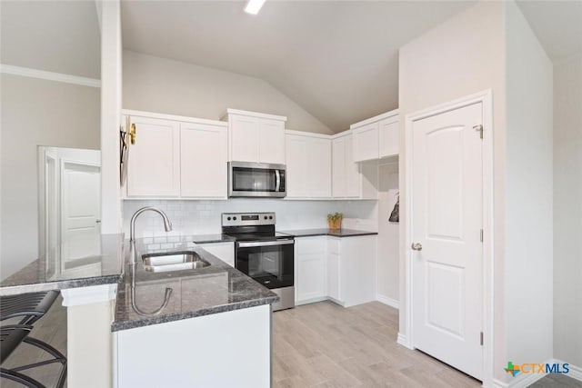 kitchen with white cabinets, stainless steel appliances, dark stone counters, and sink