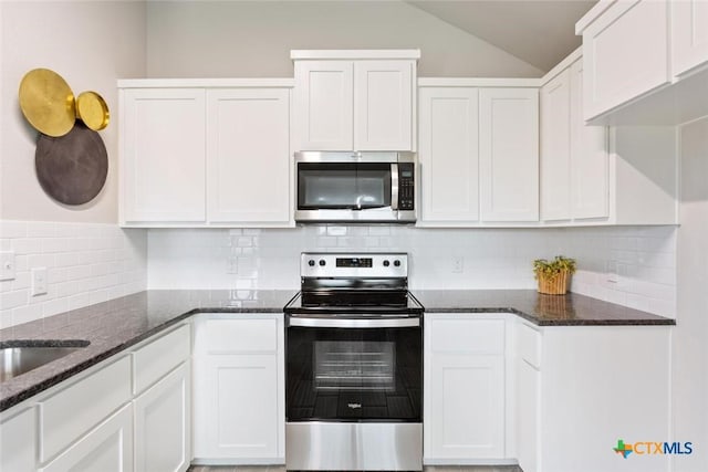 kitchen with white cabinets, appliances with stainless steel finishes, and dark stone counters