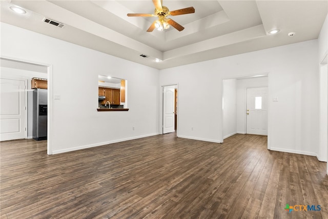 unfurnished living room featuring visible vents, a raised ceiling, baseboards, and dark wood finished floors