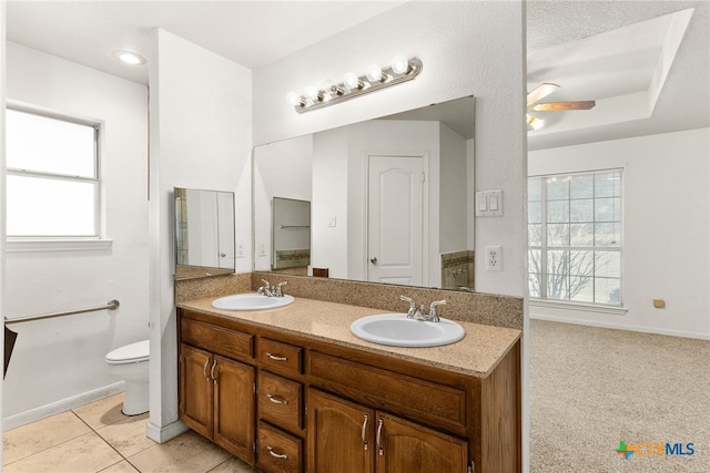 bathroom with a sink, toilet, double vanity, and tile patterned floors