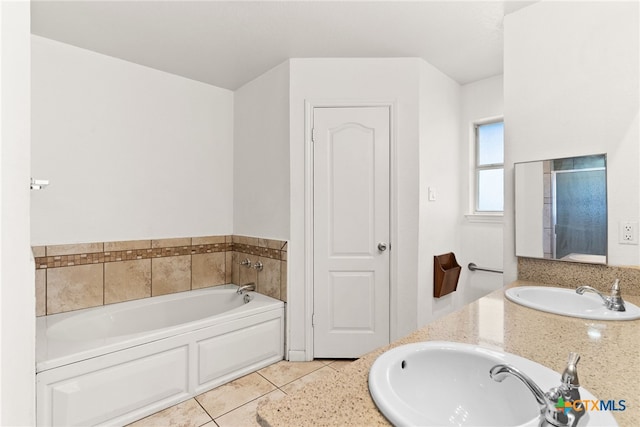 full bath with a sink, a garden tub, double vanity, and tile patterned flooring