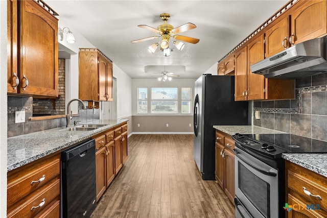 kitchen with brown cabinets, under cabinet range hood, a sink, stainless steel electric range oven, and dishwasher