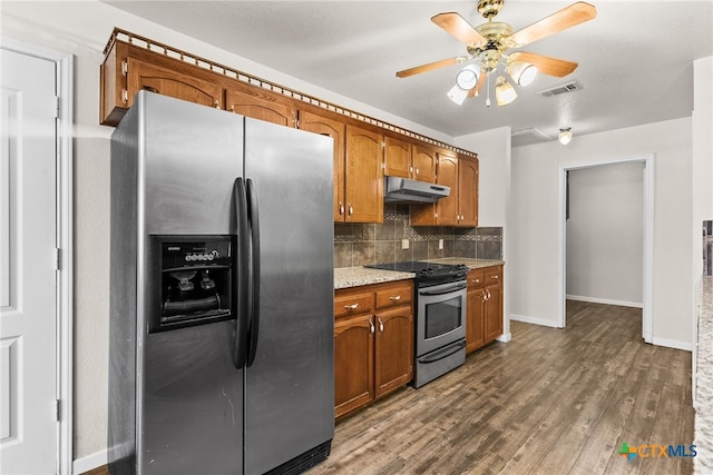 kitchen featuring tasteful backsplash, visible vents, under cabinet range hood, dark wood finished floors, and stainless steel appliances