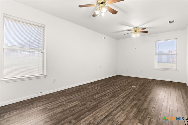 empty room with visible vents, baseboards, dark wood finished floors, and a ceiling fan