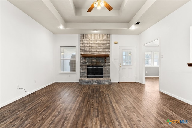 unfurnished living room with visible vents, a raised ceiling, a brick fireplace, and wood finished floors