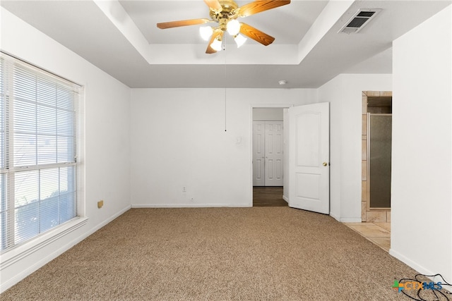 unfurnished bedroom featuring baseboards, visible vents, a raised ceiling, and carpet floors