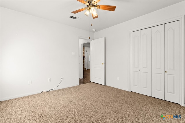 unfurnished bedroom featuring carpet flooring, visible vents, a closet, and ceiling fan