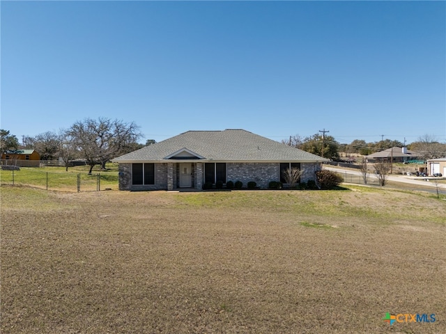 view of front of house featuring a front lawn, fence, and a shingled roof