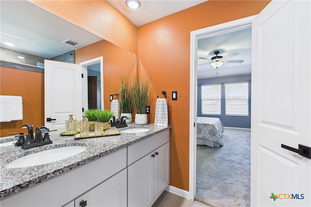 full bath with a textured wall, a ceiling fan, visible vents, and a sink