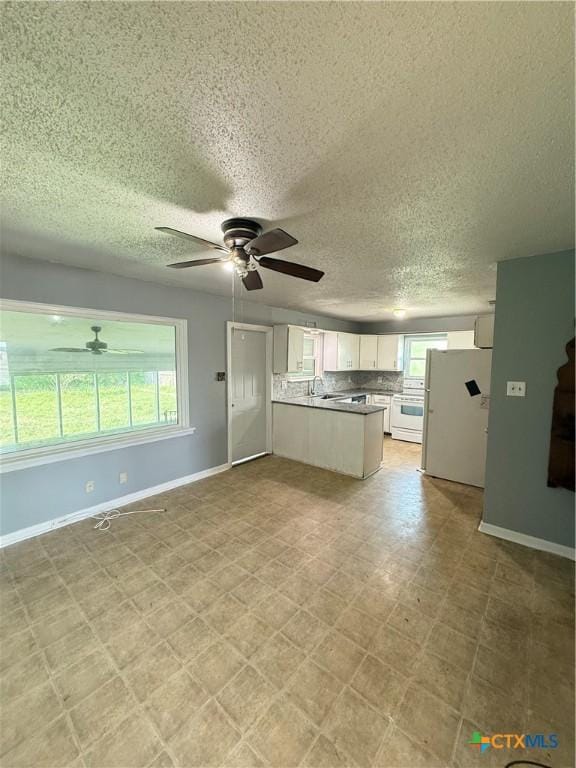 2310 Terrace Dr, Killeen, TX 76543 - unfurnished living room with baseboards, a ceiling fan, and a healthy amount of sunlight
