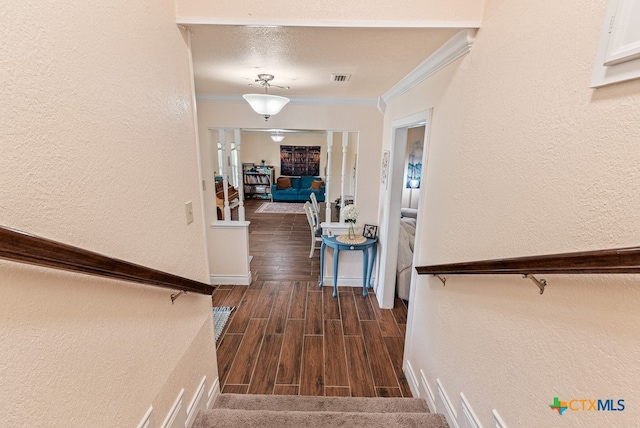 staircase featuring hardwood / wood-style flooring, a textured ceiling, and ornamental molding