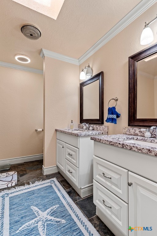 bathroom with vanity, a textured ceiling, a skylight, and ornamental molding