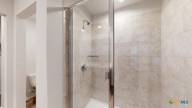 bathroom featuring toilet and a shower with door