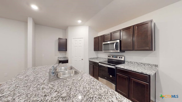 kitchen featuring stainless steel appliances, light stone countertops, sink, and dark brown cabinetry