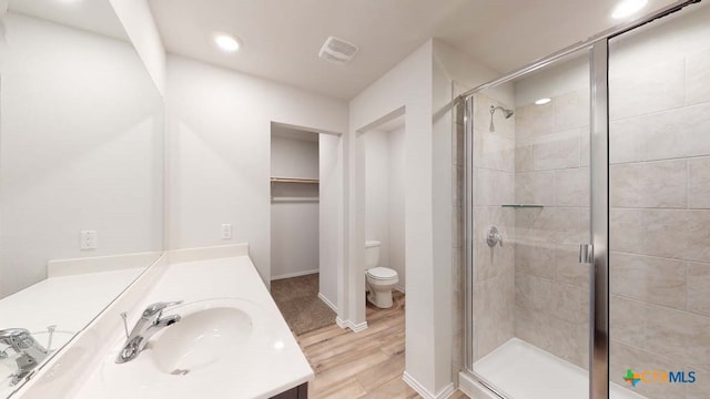 bathroom with vanity, hardwood / wood-style flooring, toilet, and a shower with door