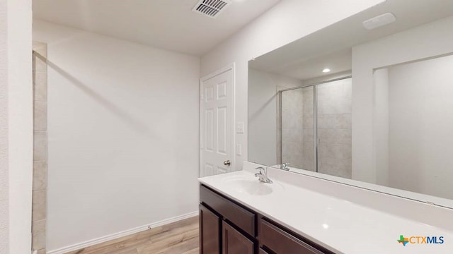 bathroom featuring hardwood / wood-style floors, vanity, and a shower with shower door