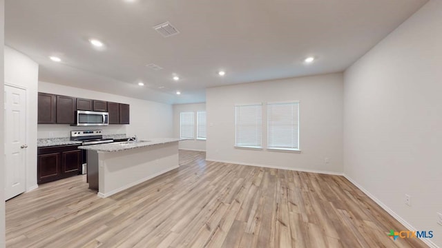 kitchen featuring light wood-type flooring, range with electric cooktop, dark brown cabinetry, sink, and a kitchen island with sink