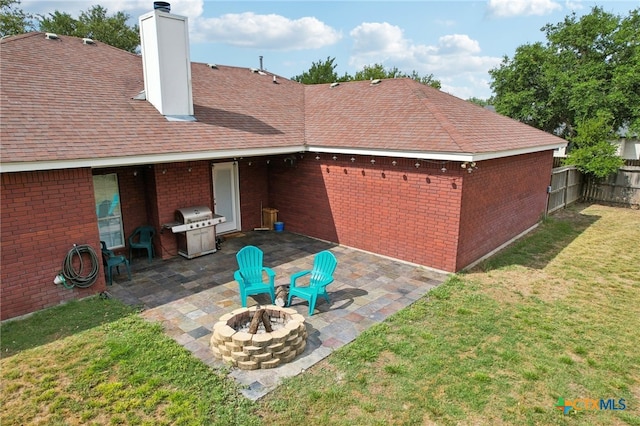 rear view of house featuring a patio area, a yard, and a fire pit