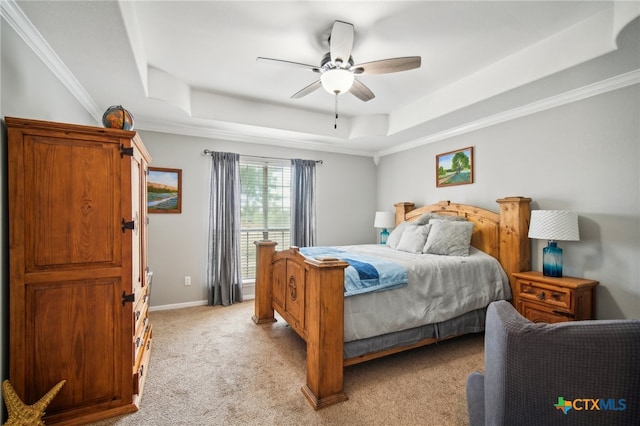 carpeted bedroom with ceiling fan, ornamental molding, and a tray ceiling