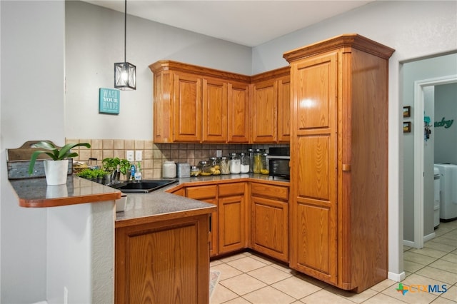 kitchen with kitchen peninsula, hanging light fixtures, light tile patterned floors, and tasteful backsplash