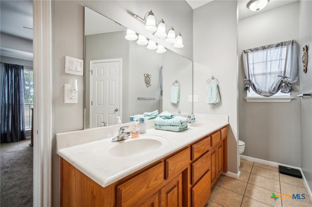 bathroom featuring toilet, vanity, a wealth of natural light, and tile patterned floors