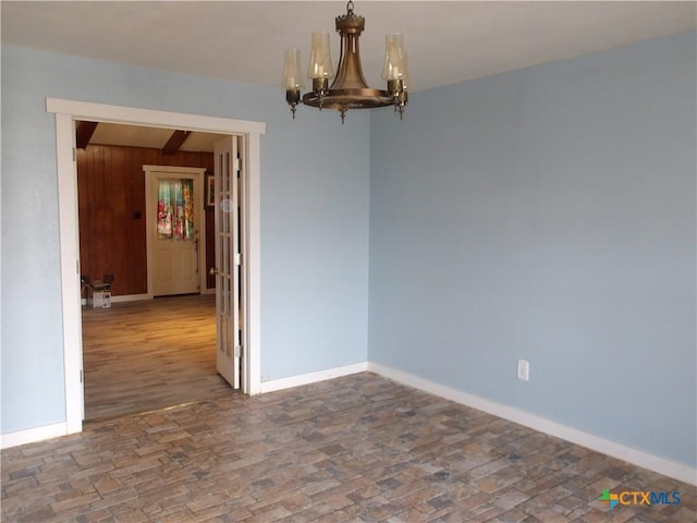 empty room with brick floor, baseboards, and a chandelier