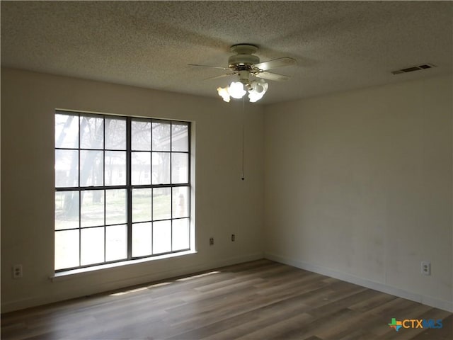 unfurnished room featuring visible vents, plenty of natural light, and wood finished floors