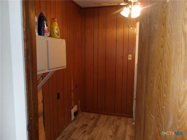 laundry area featuring wood walls, ceiling fan, cabinet space, and wood finished floors