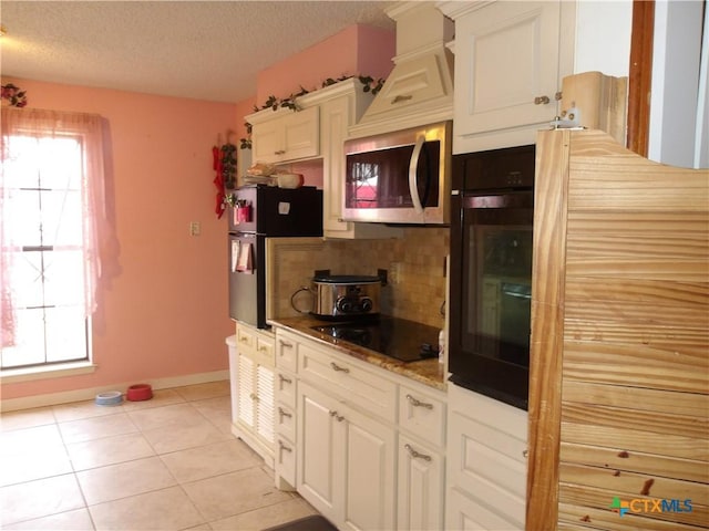 kitchen with black appliances, plenty of natural light, light tile patterned floors, and backsplash