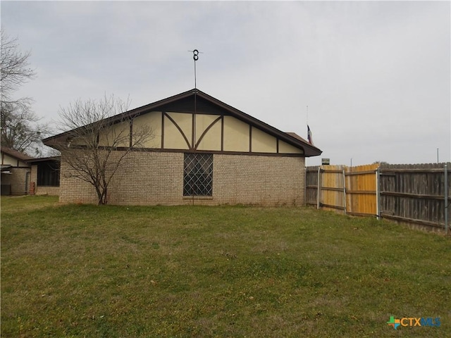 back of property with fence, a lawn, and brick siding