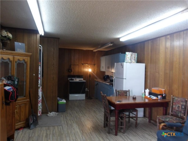 interior space with a textured ceiling, light wood finished floors, and wooden walls