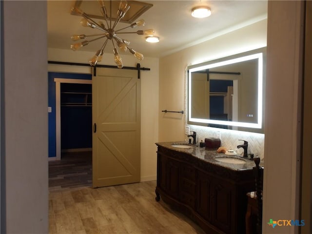 corridor with a barn door, light wood-type flooring, a sink, and baseboards